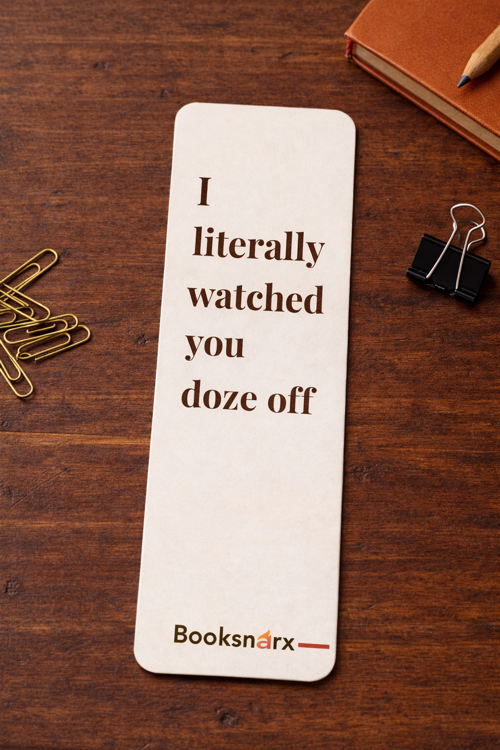 Bookmark with humorous text on a wooden surface with office supplies
